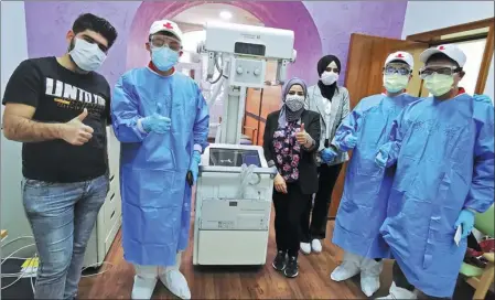  ?? XINHUA ?? Chinese experts (in blue gowns) take a photo with medical staff in Baghdad, Iraq, after installing an X-ray machine to help screen for COVID-19 cases.