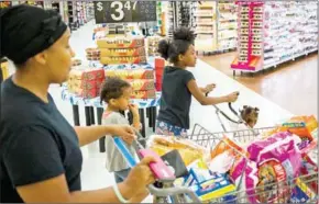  ?? RISON HILL/THE NEW YORK TIMES HAR- ?? A woman shops with her family at a Walmart in Turnersvil­le, New Jersey, on July 6.