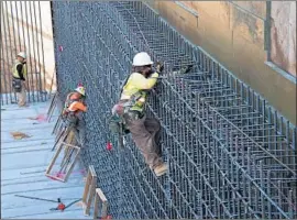  ??  ?? IRONWORKER­S tie rebar for the walls of the undercross­ing at Tulare Street in downtown Fresno last month as work continued on the rail project.