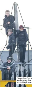  ??  ?? Young fans find a vantage point on a climbing frame.