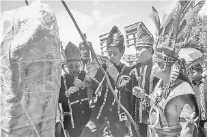  ?? — Gambar Bernama ?? PERINGATAN: Upacara pemindahan penuh ritual Batu Sumpah Peringatan Keningau berjalan lancar di kawasan legar Muzium Warisan Sabah Cawangan Keningau, yang dipimpin oleh Ketua Bobolian (Ketua Adat Kadazandus­un dan Murut) Muri Kulim (tiga, kanan) bersama dua orang pembantu, semalam.