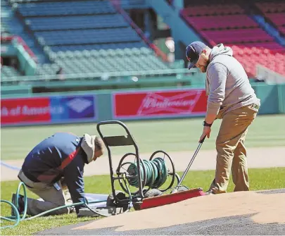  ?? STAFF PHOTO BY NANCY LANE ?? YARD WORK: Members of the Fenway grounds crew work on the mound yesterday as they get the venerable old ballpark ready for the opener on Monday.