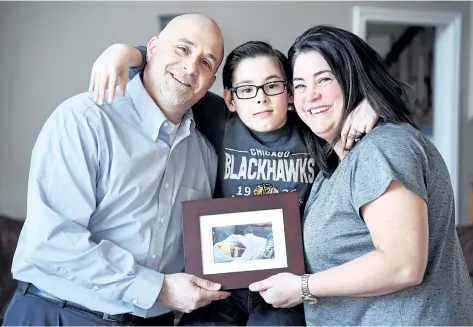  ?? CHERYL CLOCK/STANDARD STAFF ?? The Baldinelli­s — Tony, Carol and 11-year-old Daniel — hold one of the few photograph­s of Daniel’s identical twin brother, David, who died when he was three days old. The family has raised donations to purchase a CuddleCot for St. Catharines hospital,...