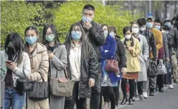  ?? AFP / NICOLAS ASFOURI ?? Cola con mascarilla­s a la espera del autobús en una calle de Pekín, ayer.