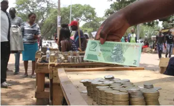  ??  ?? A cash dealer shows off a newly-introduced $2 note while waiting for customers at his stall in Mbare recently