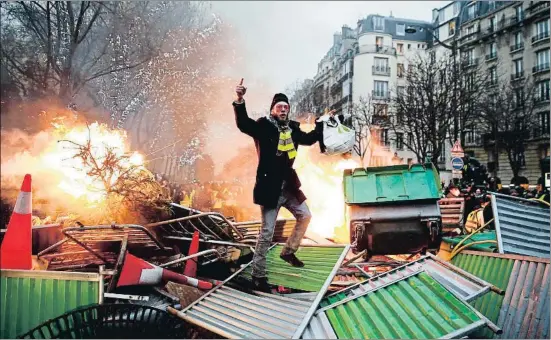  ?? ABDUL ABEISSA / AFP ?? Un miembro de los chalecos amarillos, sobre una barricada en llamas ayer en una calle de París