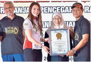  ??  ?? Job well done: Malaysia Book of Records official Gillian Ooi handing over the certificat­e to Mohd Shukri as Dr Wan Azizah and Khalid (left) look on during the event.