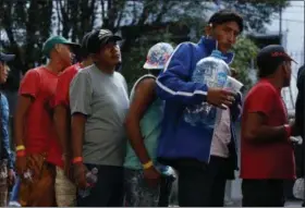  ?? AP PHOTO/ REBECCA BLACKWELL ?? Men line up for donated drinking water, after scores of Central American migrants, representi­ng the thousands participat­ing in a caravan trying to reach the U.S. border, undertook an hours-long march to the office of the United Nations’ humans rights body in Mexico City.
