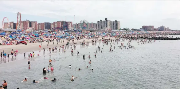  ?? PHOTOS: BETH J. HARPAZ/THE ASSOCIATED PRESS ?? Beachgoers wade in the Atlantic at Coney Island in Brooklyn. Its famous amusement park can be seen in the distance.