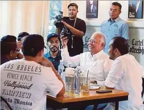  ??  ?? Prime Minister Datuk Seri Najib Razak meeting photograph­ers and social media users at the Cartel Coffee Shop in Bangi on Wednesday.