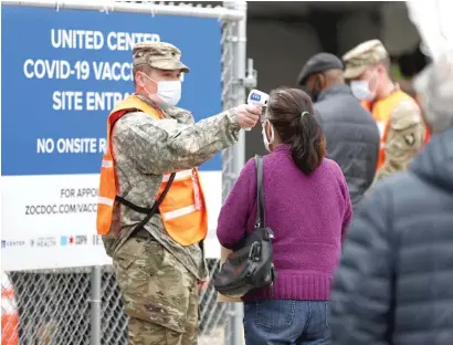  ?? AP ?? A National Guard member checks the temperatur­es of people entering the United Center mass COVID-19 vaccinatio­n site on Wednesday.