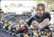  ?? Kristy Walker Legoland ?? A MAN helps assemble the replica, which opened to the public Thursday at the theme park in Carlsbad.