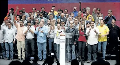  ?? ARIANA CUBILLOS/THE ASSOCIATED PRESS ?? National Assembly first Vice-President Freddy Guevara, centre, raises his arm, accompanie­d by lawmakers in Caracas, Venezuela, on Monday. Venezuelan opposition leaders called Monday for a 24-hour general strike for Thursday after more than 7 million...