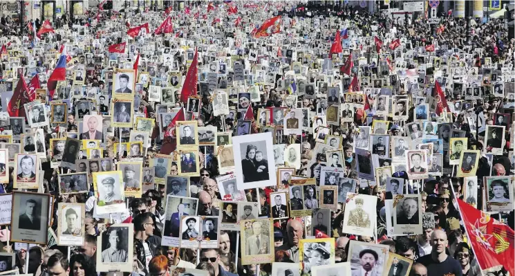  ?? DMITRI LOVETSKY/THE ASSOCIATED PRESS ?? Residents take part in the Immortal Regiment march in St. Petersburg on May 9, holding portraits of relatives who fought in the Second World War.