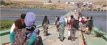  ?? (Reuters) ?? YAZIDIS WHO fled ISIS cross a bridge in Iraq in 2014.