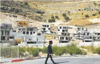  ??  ?? A MAN walks past constructi­on sites around Givat Ze’ev. (Ammar Awad/Reuters)