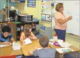  ?? Doug Walker / Rome News-Tribune ?? The Floyd County school system is the county’s second-largest employer. Kitty Beaird (right) teaches a class at Cave Spring Elementary School. Youngsters Fernando Ramirez (from left), Sheallyn Jones and Alex Cord make notes during a grammar lesson.