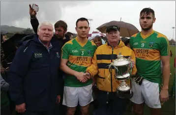  ??  ?? Mick Hagan and Ray Barry present the Swan Cup to Laragh captains Peter Merrigan and Damien Hanlon.