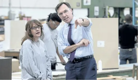  ?? PAUL CHIASSON/THE CANADIAN PRESS ?? Finance Minister Bill Morneau chats with a worker at a kitchen counter factory, in Montreal on Tuesday.