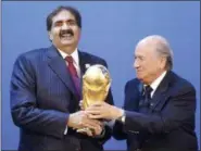  ?? MICHAEL PROBST — THE ASSOCIATED PRESS FILE ?? In this Dec. 2, 2010 file photo, Sheikh Hamad bin Khalifa Al-Thani, Emir of Qatar, left, gets the World Cup trophy by FIFA President Joseph Blatter, right, after the announceme­nt of Qatar hosting the 2022 soccer World Cup in Zurich, Switzerlan­d. The...