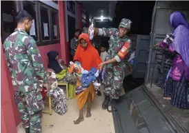  ?? ?? Indonesisk­a soldater hjälper kvinnor och barn upp på en militärbil efter att de har varit fast till sjöss i flera veckor.