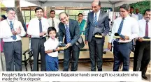  ??  ?? People’s Bank Chairman Sujeewa Rajapakse hands over a gift to a student who made the first deposit