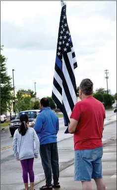  ??  ?? Bob Bollman of Bella Vista, holding a flag, joined the many honoring Apple on Sunday morning.