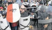  ?? Steve Helber Associated Press ?? WHITE NATIONALIS­T demonstrat­ors use shields to guard the entrance to a Charlottes­ville, Va., park on Saturday.