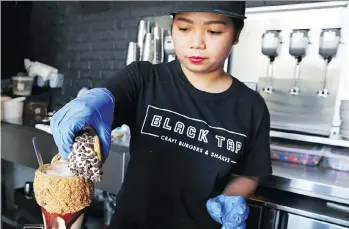  ?? JON GAMBRELL/THE ASSOCIATED PRESS ?? Maria Gagua prepares a milkshake at the Black Tap in Dubai, United Arab Emirates. Establishm­ents such as Black Tap and Dubai’s two main distributo­rs are increasing­ly stocking American craft beer, breaking new ground among Gulf nations, some of which...