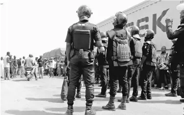  ??  ?? Ivory Coast security forces stand in front of demobilise­d ex-rebel fighters at the checkpoint at the entrance of Bouake, Ivory Coast. — AFP photo