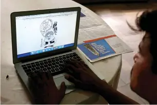  ?? Reuters ?? A man reads a newspaper’s website with a cartoon depicting an alien creature, on a computer screen at a library in Karachi. —