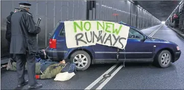  ?? Pictures: PA ?? Police approach demonstrat­ors chained to a car blocking the tunnel at Heathrow yesterday