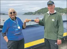  ?? ?? Seil’s Sue Fenton passes the RowAround Scotland 2021 baton to Stuart Cunningham, chairperso­n of Oban’s coastal rowing club, in June this year.