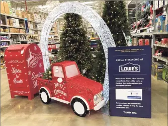  ?? Associated Press ?? A mailbox for letters to Santa Claus stands with a Christmas display next to a sign encouragin­g social distancing in a Lowe’s store Friday in Northglenn, Colo. Add last-minute holiday shopping to the list of time-honored traditions being upended by the coronaviru­s pandemic. Retailers are kicking off the holiday season earlier than ever this year in hopes of avoiding big in-store crowds and shipping bottleneck­s in November and December.