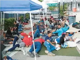  ?? WILFREDO LEE/AP ?? Recently arrived migrants wait in a garage area of the U.S. Customs and Border Protection — Marathon Border Patrol Station on Jan. 4 in Marathon. Gov. Ron DeSantis, a top Republican presidenti­al prospect, has activated the National Guard.