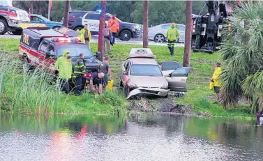  ?? WAYNE K. ROUSTAN/STAFF ?? Broward Sheriff Fire Rescue pulls a Honda out of a lake off northbound Interstate 95, just north of the Hillsboro Boulevard exit Deerfield Beach on Thursday. Two were killed; divers were searching under water for a possible third victim. in