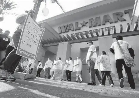  ?? Mark Boster Los Angeles Times ?? THIS WAL-MART store in Pico Rivera that was closed five months ago will reopen this fall. The store’s closure rocked the community, where the local Wal-Mart was the city’s second-largest employer. Above, workers and union members are shown protesting...