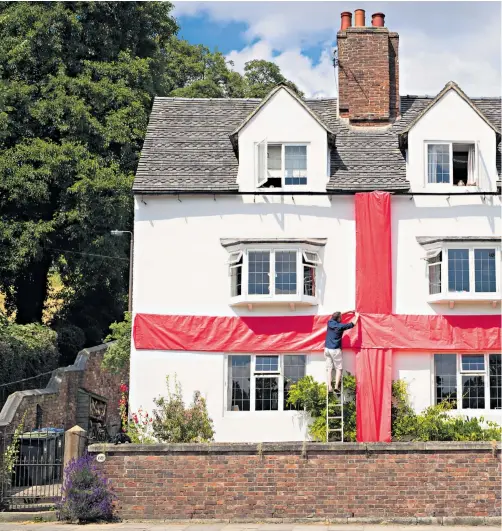  ??  ?? Robin Cantellow parcels up his 17th century house in Ashbourne, Derbys with a 33ft by 50ft red, celebrator­y ribbon, which he hopes will still be in place for the World Cup final