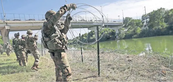  ??  ?? Soldados estadounid­enses instalan alambre de púas, alrededor del río Grande, en Texas. Trump dijo que los militares podrían llegar a los 15 mil.