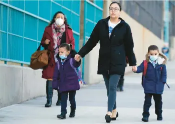  ?? SETH WENIG/AP ?? Young children wearing face masks are taken to a school on March 7 in New York.