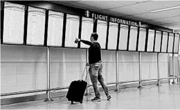  ?? CHARLIE RIEDEL/AP ?? A man checks flight info at normally full boards at Hartsfield-Jackson airport in Atlanta.