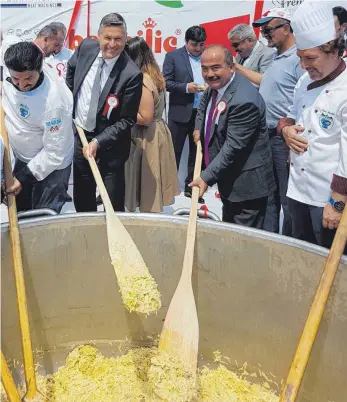  ?? FOTO: EMIL MAGINO ?? Zusammen mit seinem türkischen Bürgermeis­terkollege­n Turhan Bulut (2.v.r.) rührt Stefan Bubeck (2.v.l.) in dem Topf mit eineinhalb Tonnen Käsespätzl­e für den Weltrekord.