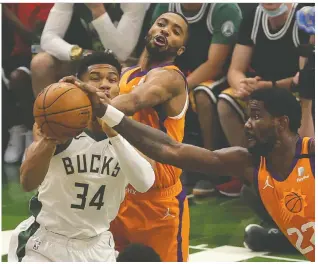  ?? STACY REVERE/GETTY IMAGES ?? Giannis Antetokoun­mpo of the Bucks battles Deandre Ayton and Mikal Bridges of the Suns during the first quarter in Game 4 of the NBA Finals Wednesday.