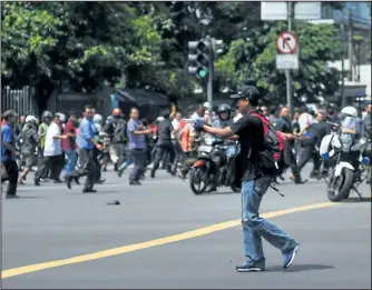  ?? VERI SANOVRI/XINHUA/REUTERS ?? A man is seen aiming a gun towards the crowd in central Jakarta, Indonesia, in this picture provided to Reuters by Xinhua News Agency on Thursday.
