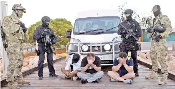  ??  ?? Australian Federal Police SWAT officers watching over suspects after 1.2 tonnes of methamphet­amine commonly known as ‘ice’ was intercepte­d being offloaded ffrom a boat, the Valkoista, in Geralton, Western Australia. — AFP photo