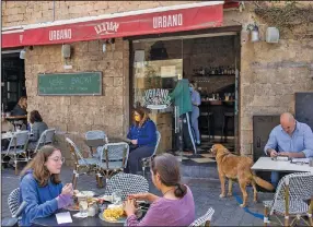  ?? (AP/Ariel Schalit) ?? People in Tel Aviv, Israel, eat at a restaurant Sunday as restrictio­ns are eased after months of government-imposed shutdowns.