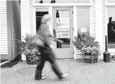  ?? ROBERT F. BUKATY/AP ?? A shopper walks past one of several vacant retail spaces among outlet shops last month in Freeport, Maine.