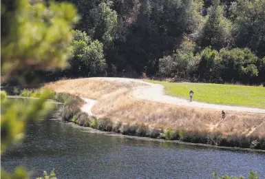  ?? Photos by Jessica Christian / The Chronicle ?? Pedestrian­s walk around Boronda Lake in Foothills Park, which has been open to Palo Alto residents only.