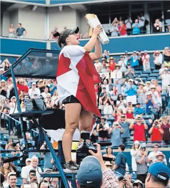  ?? NATHAN DENETTE THE CANADIAN PRESS ?? Bianca Andreescu celebrates with her trophy while standing on the umpire’s chair after winning the Rogers Cup women’s tennis final in Toronto on Sunday. Her opponent, Serena Williams, was forced to retire early.