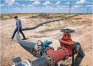  ??  ?? A hose that connects a water well to Layne Christense­n’s new pipeline, which runs 20 miles from Pecos in far West Texas to oil and gas fields to the north.